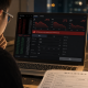 Realistic editorial image of a mainland Chinese investor viewing an overseas brokerage app with trading restrictions on a laptop.