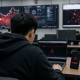 Realistic editorial image of an anonymous internet user in a Chinese computer lab facing blocked connection warnings.