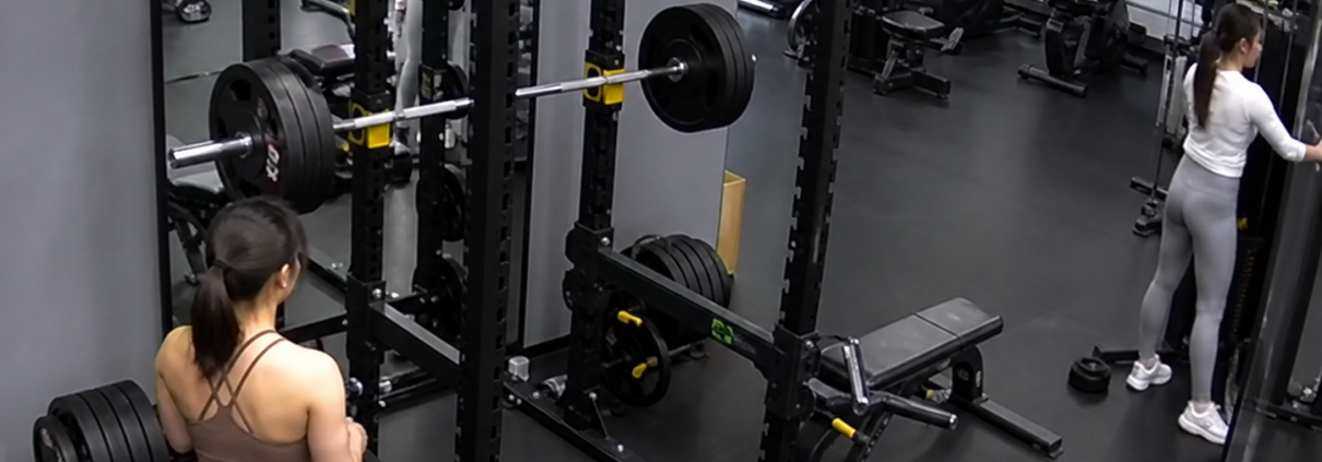 CCTV-style view inside a Chinese gym showing a squat rack and loaded barbell before a safety incident