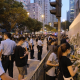 Police and plainclothes officers surround a woman holding a yellow paper flower in Causeway Bay on Hong Kong's June 4 anniversary.